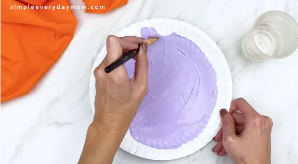 hands painting paper plate purple