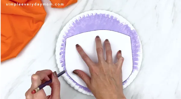 hands tracing vampire face template onto paper plate