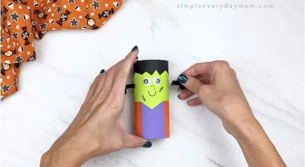hands gluing bolts to toilet paper roll frankenstein craft