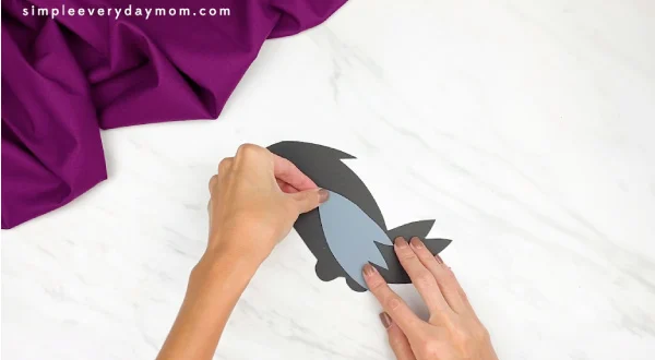 hands gluing wing to paper crow craft