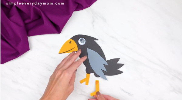hands gluing feet to paper crow craft