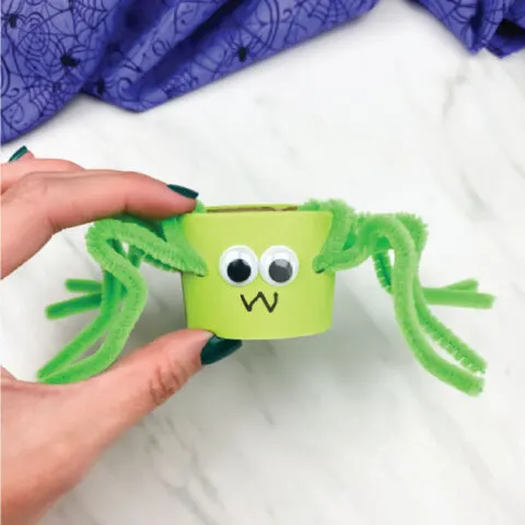hand holding toilet paper roll pipe cleaner spider in green