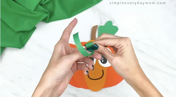 hands twisting green paper around finger
