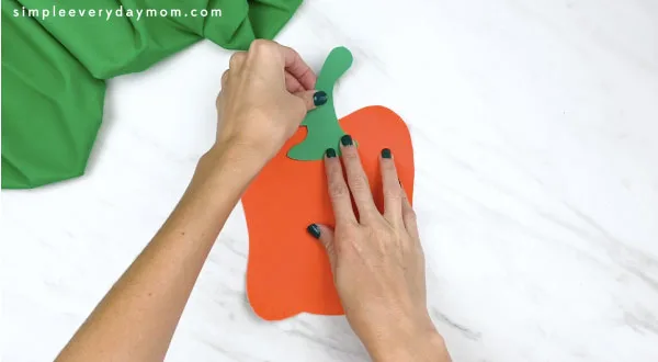 Hands gluing stem on paper plate spookley