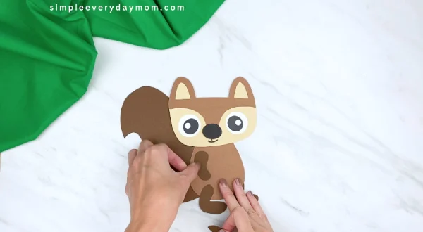 hands gluing paper squirrel arms onto craft