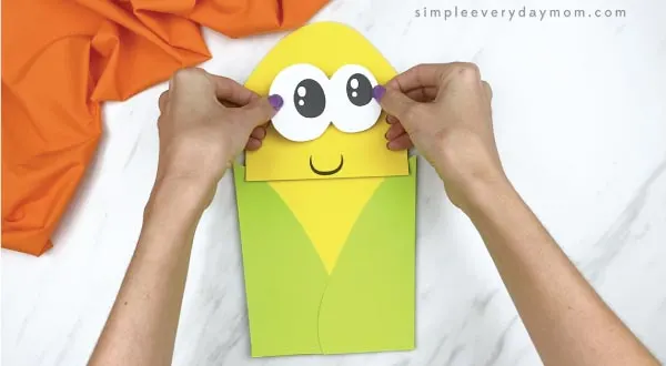 hands gluing eyes to paper bag corn craft