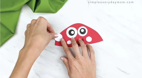 hands gluing white spots onto paper mushroom craft