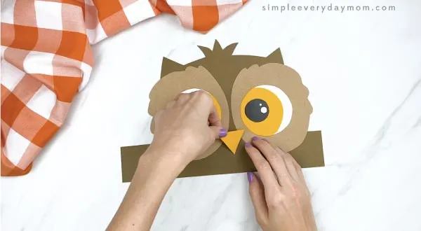 hands gluing beak to headband owl craft