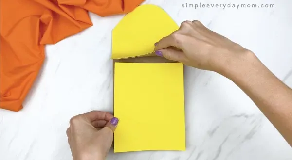 hands gluing yellow paper on paper bag corn craft