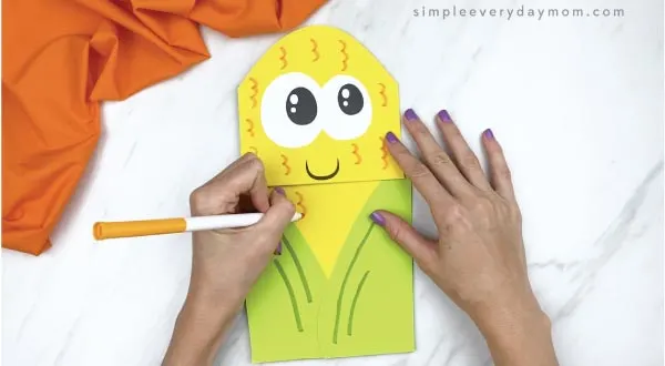 hands drawing on paper bag corn craft with marker
