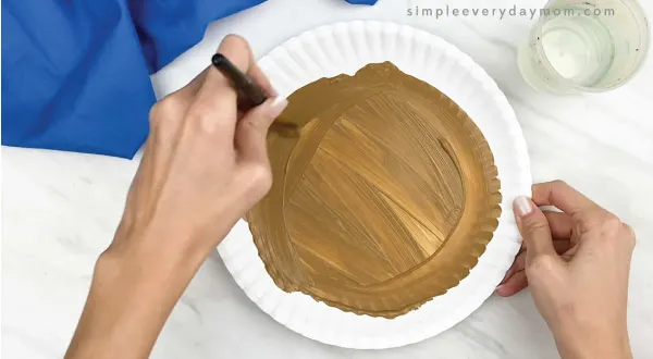 hands painting paper plate brown