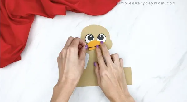 hands gluing beak onto headband turkey craft