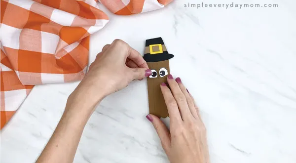 hands gluing eyes onto popsicle stick turkey craft