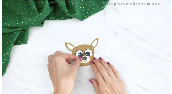 hands gluing nose to reindeer finger puppet craft