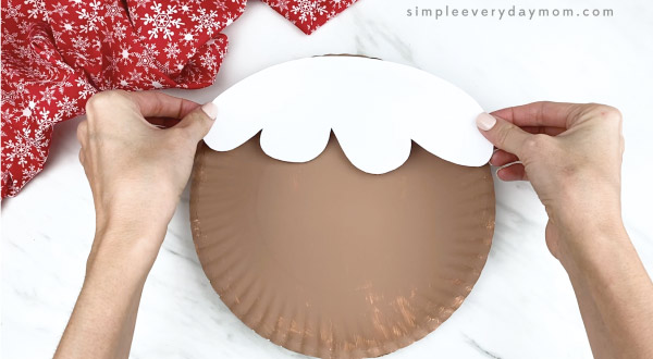 hands gluing icing hair to girl paper plate gingerbread craft