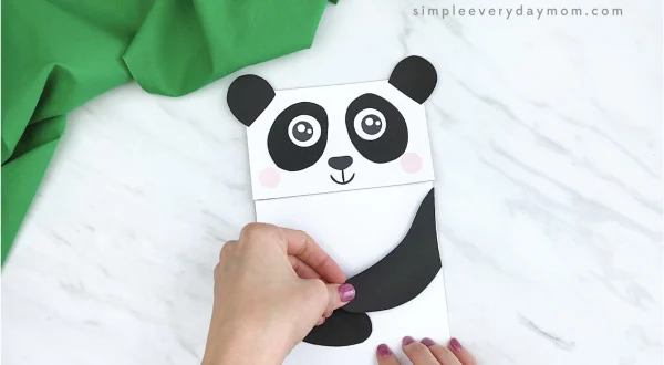 hands gluing arms to paper bag panda craft