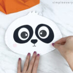 hands gluing cheeks to paper plate panda craft