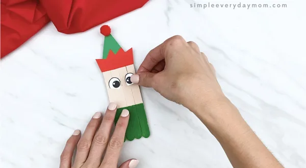 hands gluing eyes onto popsicle stick craft