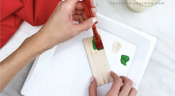 hands gluing popsicle sticks green