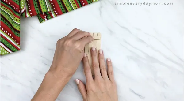 hands gluing 4 popsicle sticks together