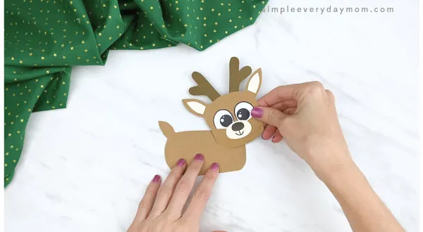 hands gluing reindeer head to finger puppet body