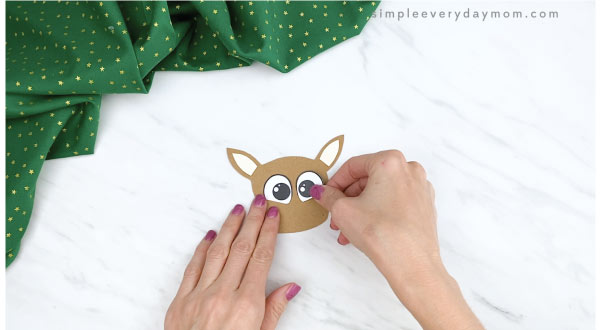 hands gluing eyes to reindeer finger puppet craft