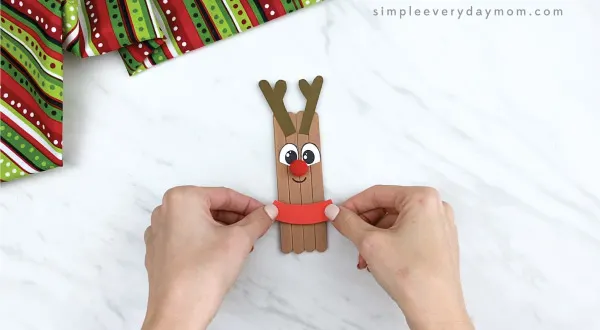 hands gluing collars on popsicle stick reindeer
