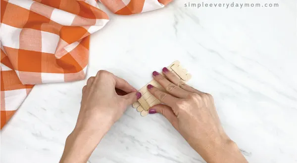 hands gluing popsicle stick together