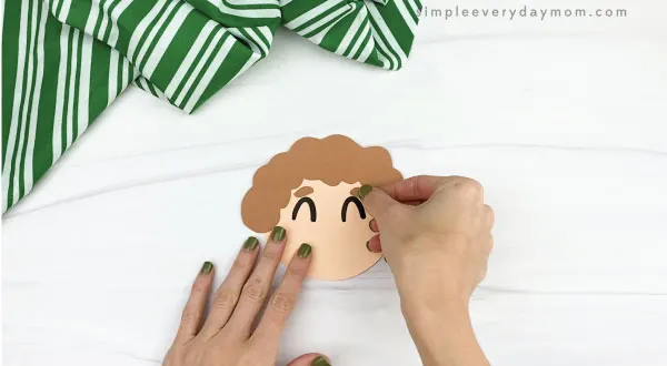 hands gluing eyebrows to elf ornament craft