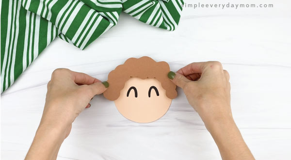 hands gluing hair to elf ornament craft