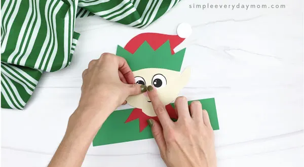 hands gluing nose to elf headband craft