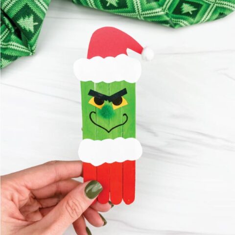 hand holding popsicle stick grinch craft