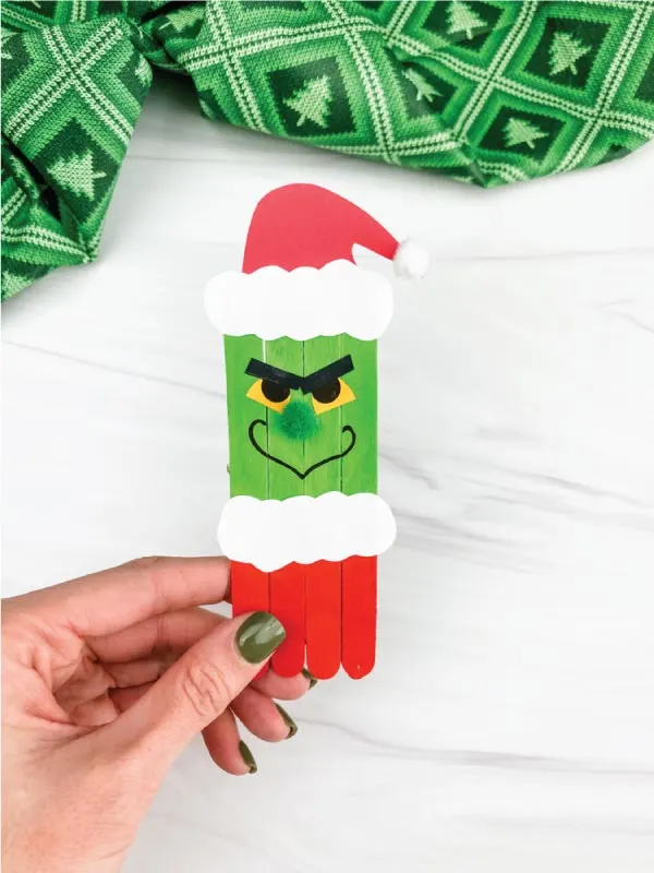 hand holding popsicle stick grinch craft