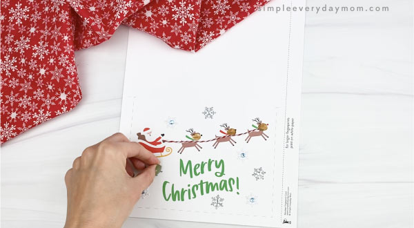 hands placing snowflake stickers on reindeer christmas card