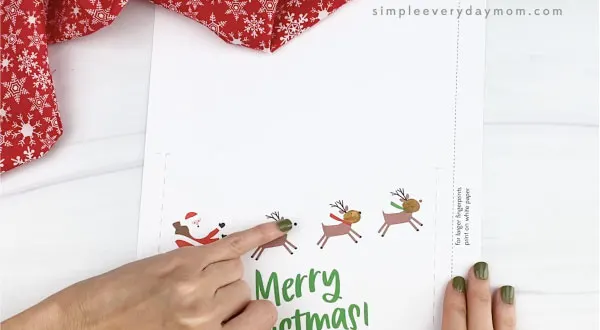 hands making paint fingerprint on reindeer card