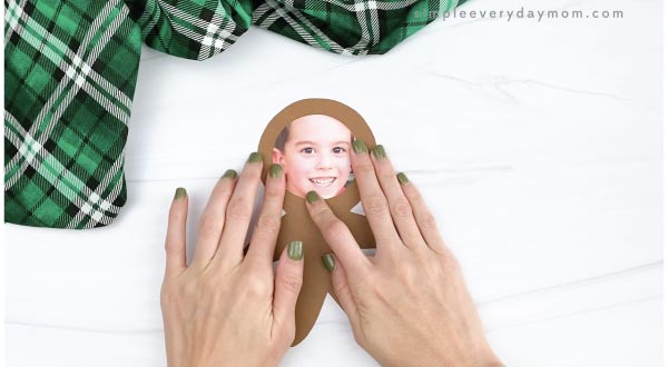 hand gluing child photo to gingerbread man craft