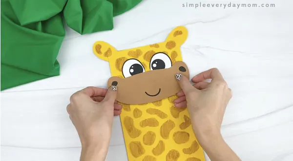 hands gluing mouth to paper bag giraffe craft