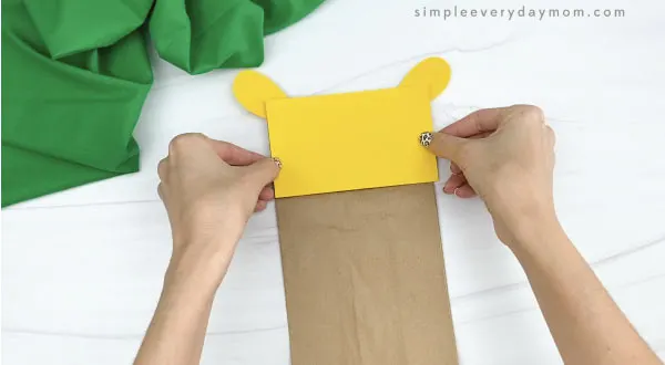 hands gluing head to paper bag giraffe craft