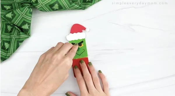 hands gluing nose onto popsicle stick grinch craft
