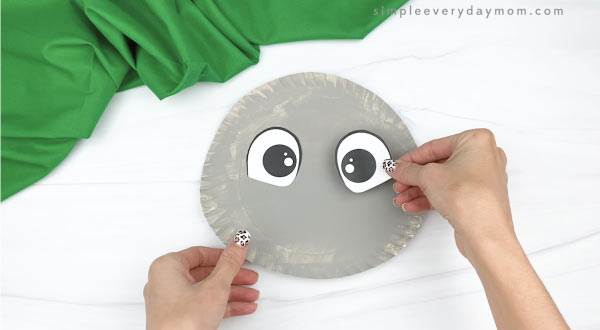 hand gluing eye to paper plate koala