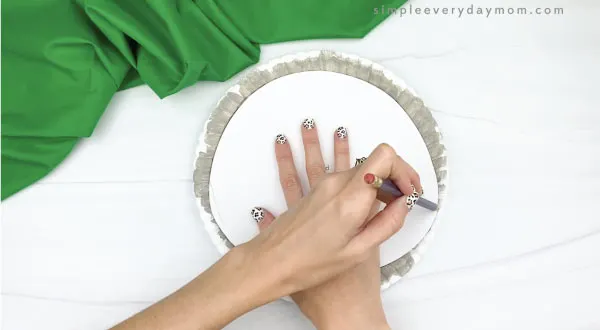 hand tracing template onto paper plate