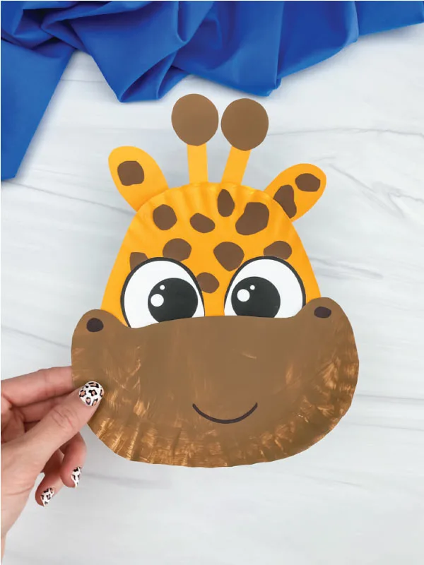hand holding brown and yellow paper plate giraffe craft