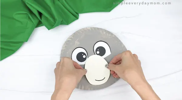 hand gluing mouth to paper plate koala