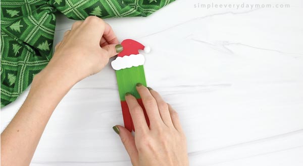 hands gluing hat onto popsicle stick grinch craft