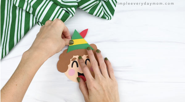 hands gluing hat to elf ornament craft