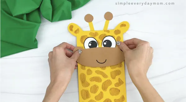 hands gluing horns to paper bag giraffe craft