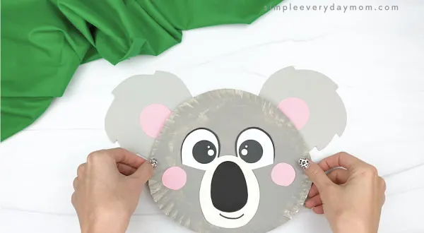 hand gluing ears to paper plate koala craft