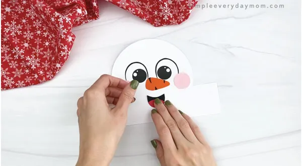 hands gluing mouth to snowman headband craft