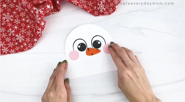 hands gluing cheeks to snowman headband craft