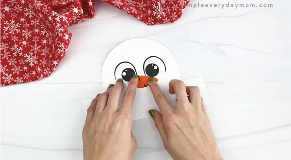 hands gluing nose to snowman headband craft